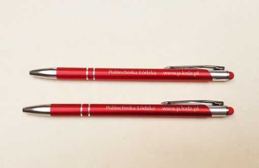 Two burgundy pens with the inscription Lodz University of Technology placed parallel on a light background
